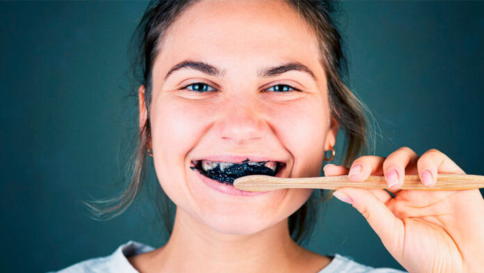 Mujer aplicándose en los dientes un remedio casero para blanquearlos